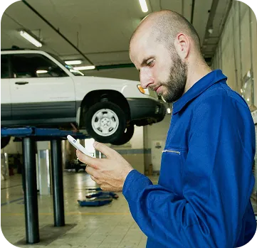 A mechanic in a workshop checking his phone
